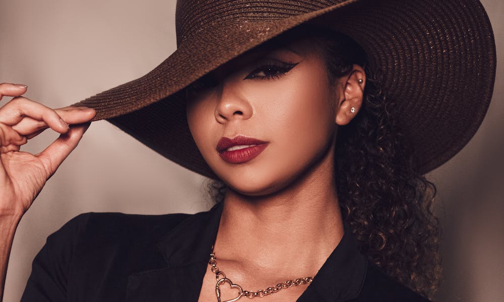 Charming female model with red lips in fashionable outfit and headwear looking at camera against gray background in light studio .pexels