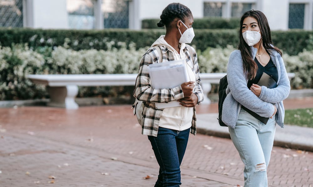 Multiethnic students with folders walking in park .pexels