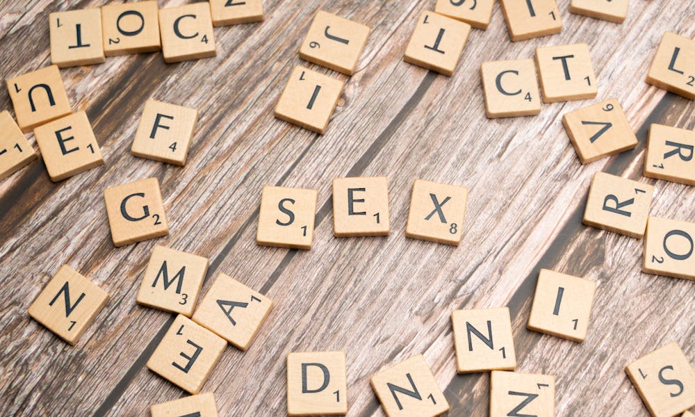 Scrabble letters spelling out sex on a wooden table .pexels