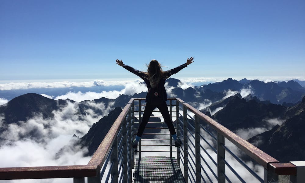 Person Standing on Hand Rails With Arms Wide Open Facing the Mountains and Clouds .pexels