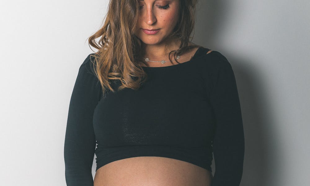 A pregnant woman in black top posing for a photo .pexels