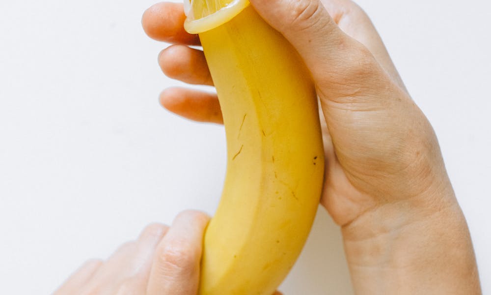 Person Wrapping Condom on Banana .pexels