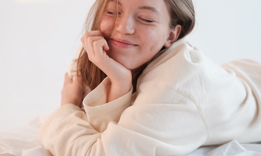 Optimistic female resting on bed with closed eyes .pexels