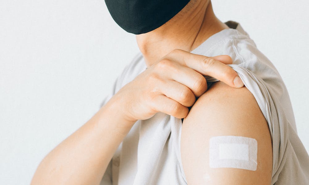 Man in White Shirt Wearing Black Face Mask Showing Vaccination on Arm .pexels
