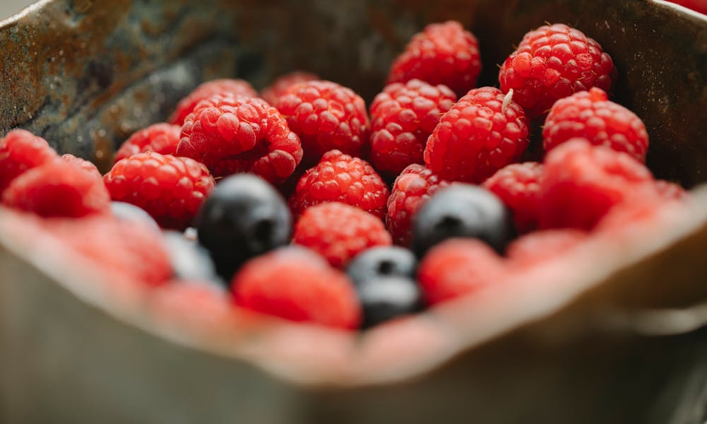 Appetizing ripe raspberries and blueberries in bowl .pexels