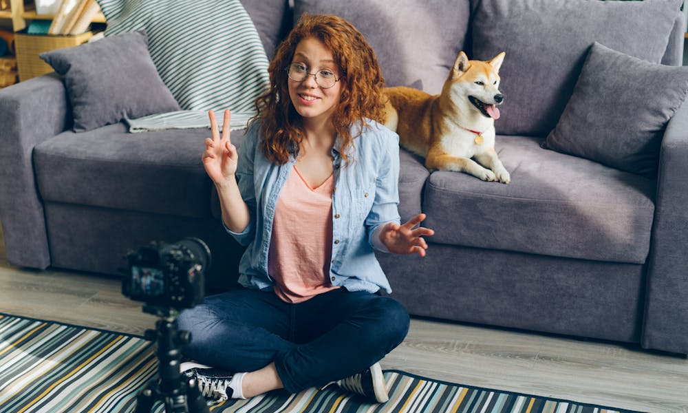 A woman sitting on the floor with a dog and a camera .pexels