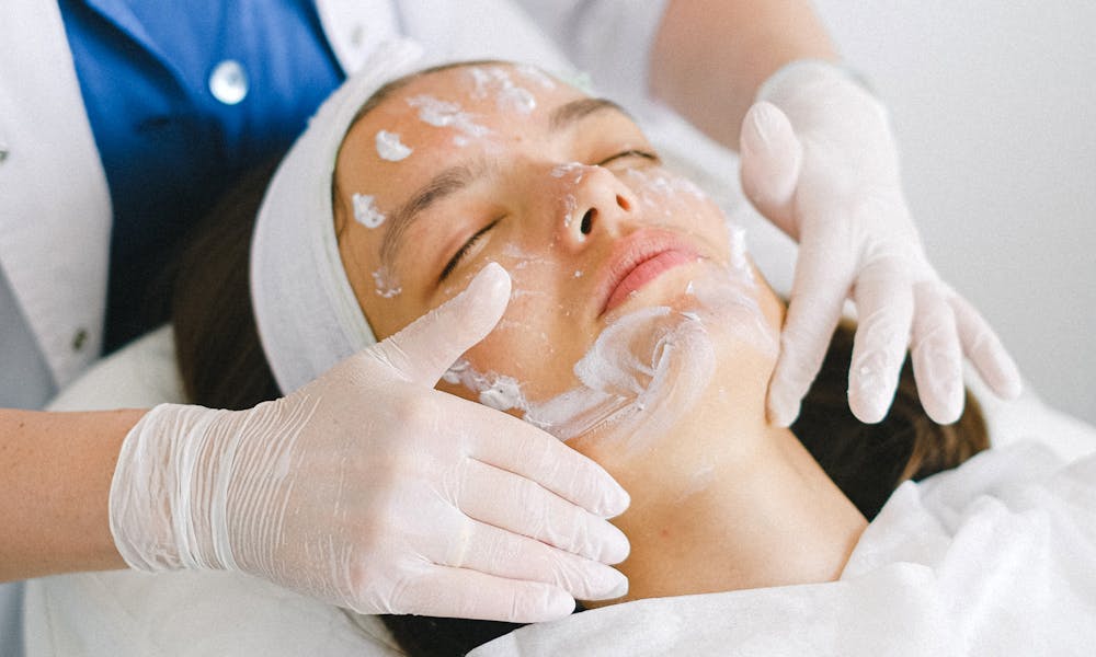 From above of crop faceless cosmetician applying facial mask on customer face during cosmetic procedure in modern spa salon .pexels