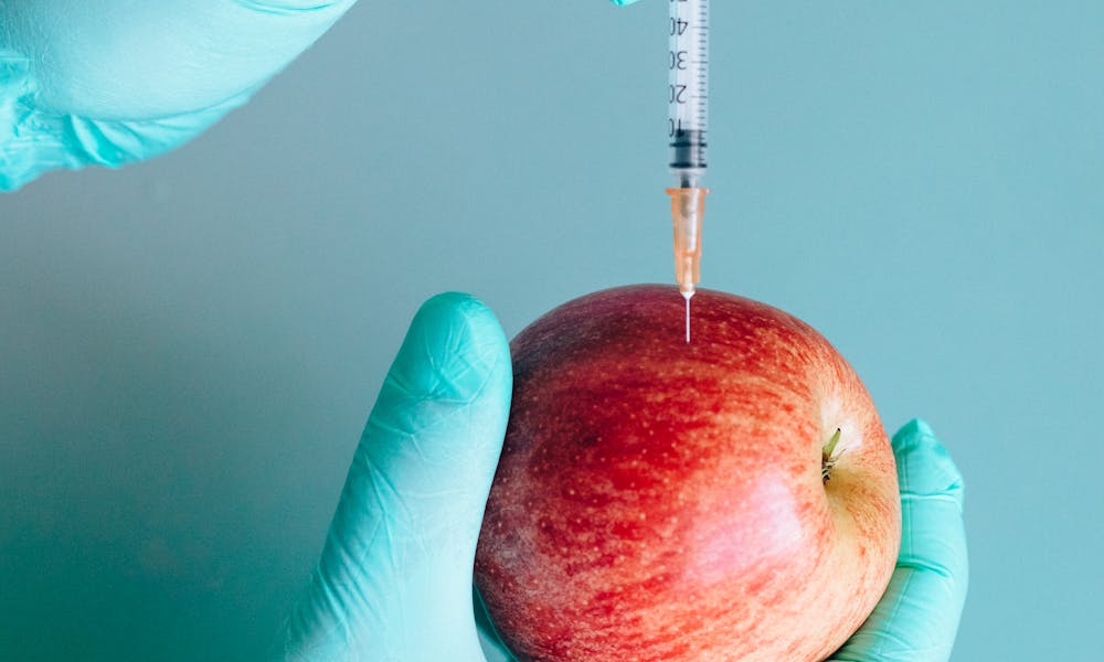 Person Injecting a Red Apple by Using a Syringe .pexels