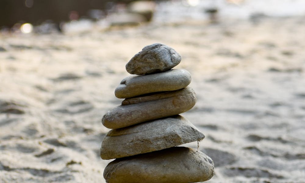 A stack of rocks on the beach near a river .pexels