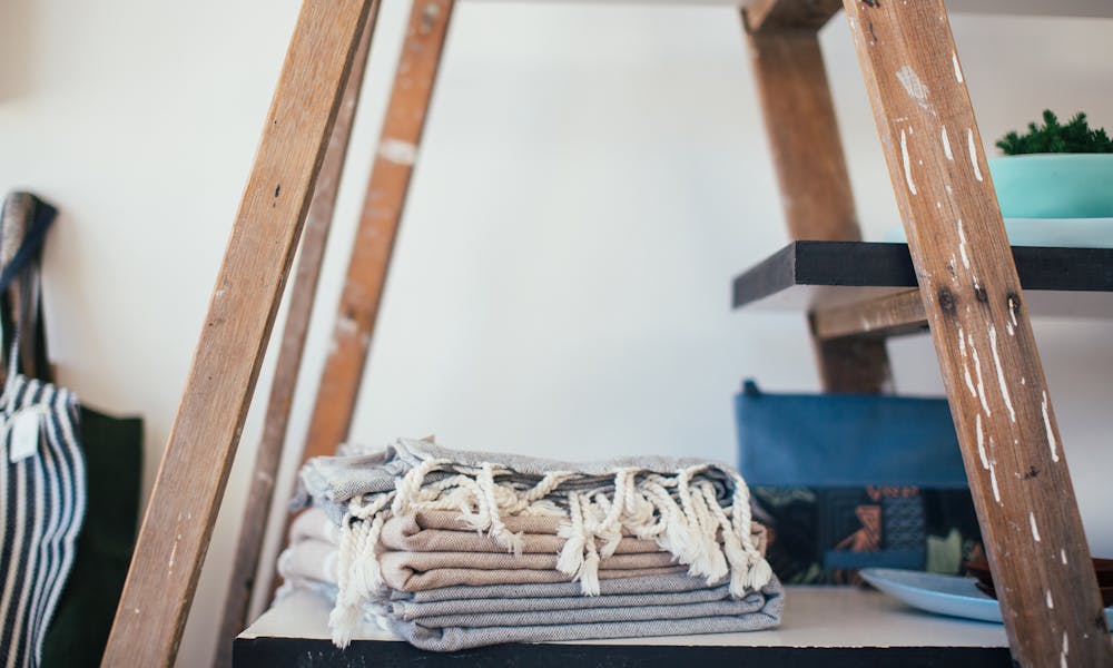 Stack of clean cotton towels with tassels placed on shelf at home in daytime .pexels