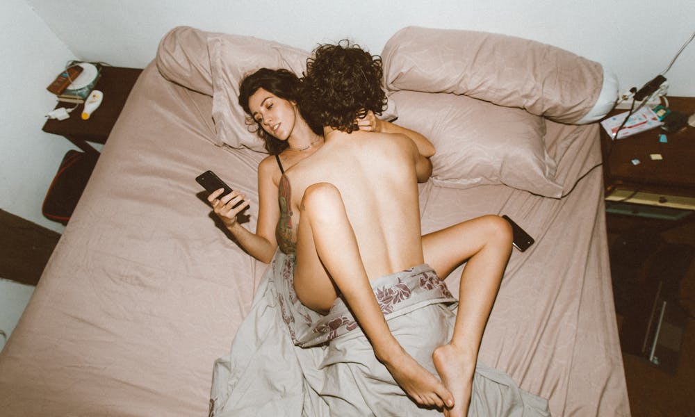 Couple being intimate and using smartphone .pexels