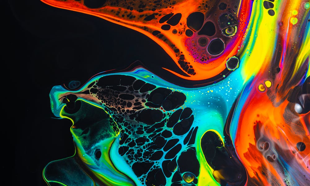 Colorful mix of neon paints swirling on black surface .pexels