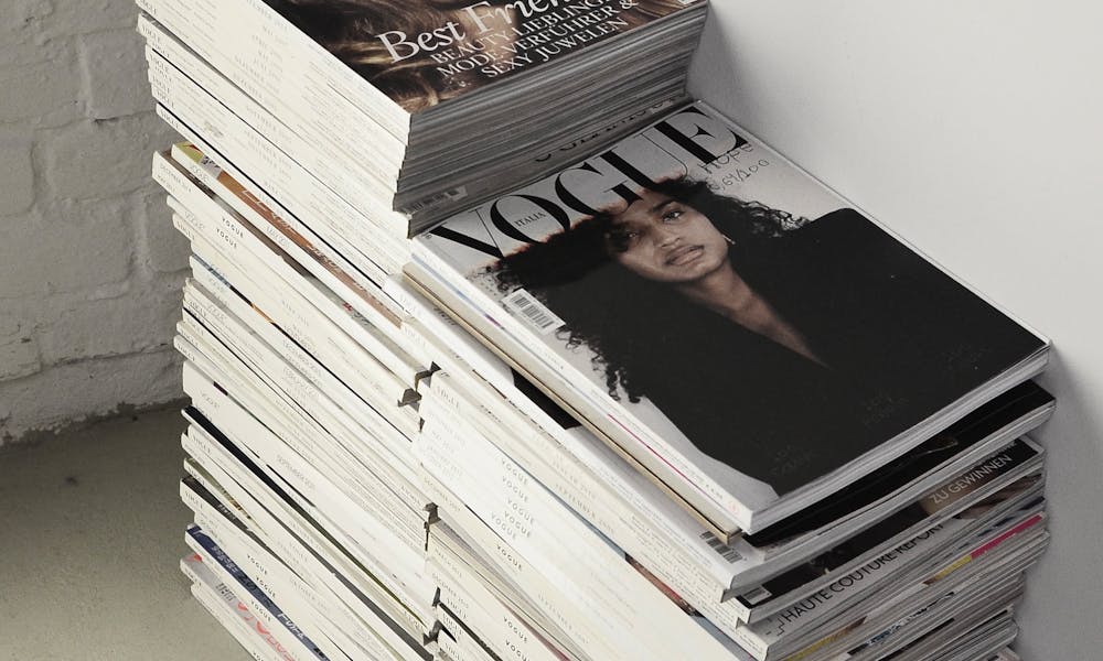 High angle many fashion magazines stacked on floor against white brick wall in studio .pexels