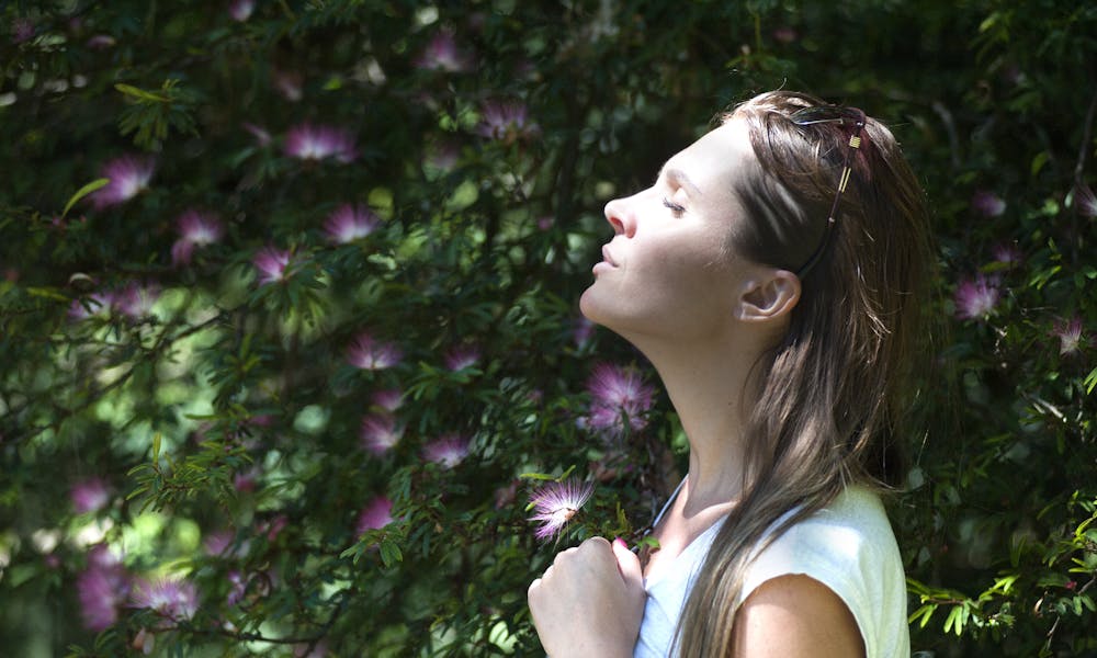 Woman Closing Her Eyes Against Sun Light Standing Near Purple Petaled Flower Plant .pexels