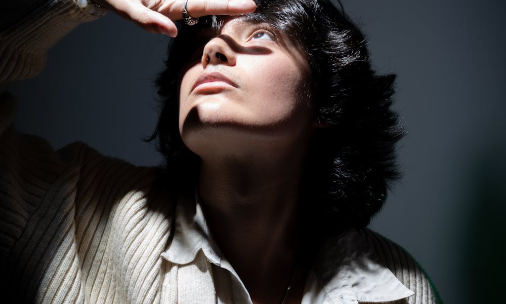 A woman in a sweater is holding her head .pexels