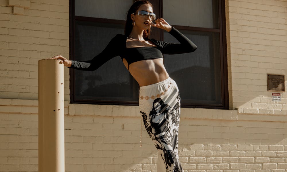A woman in a crop top and leggings poses on a pole .pexels