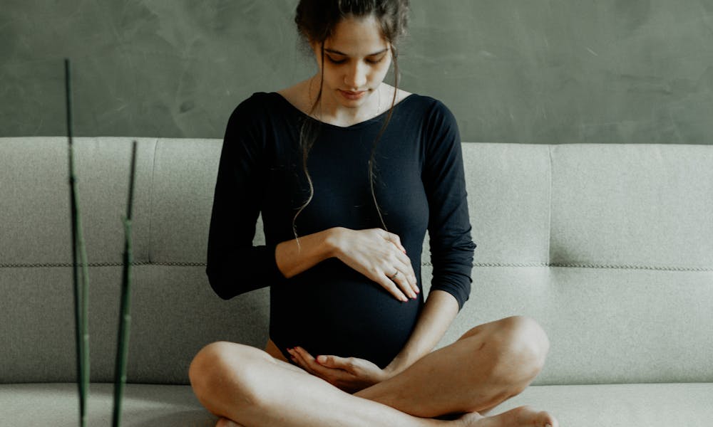 A Pregnant Woman Sitting on the Couch and Touching Her Belly .pexels