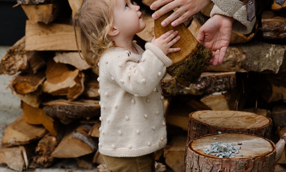 Little girl looking at father standing near firewood .pexels