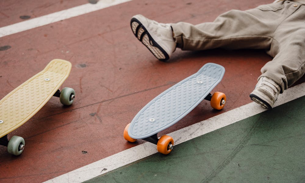 Crop unrecognizable kid lying on ground near skateboard .pexels