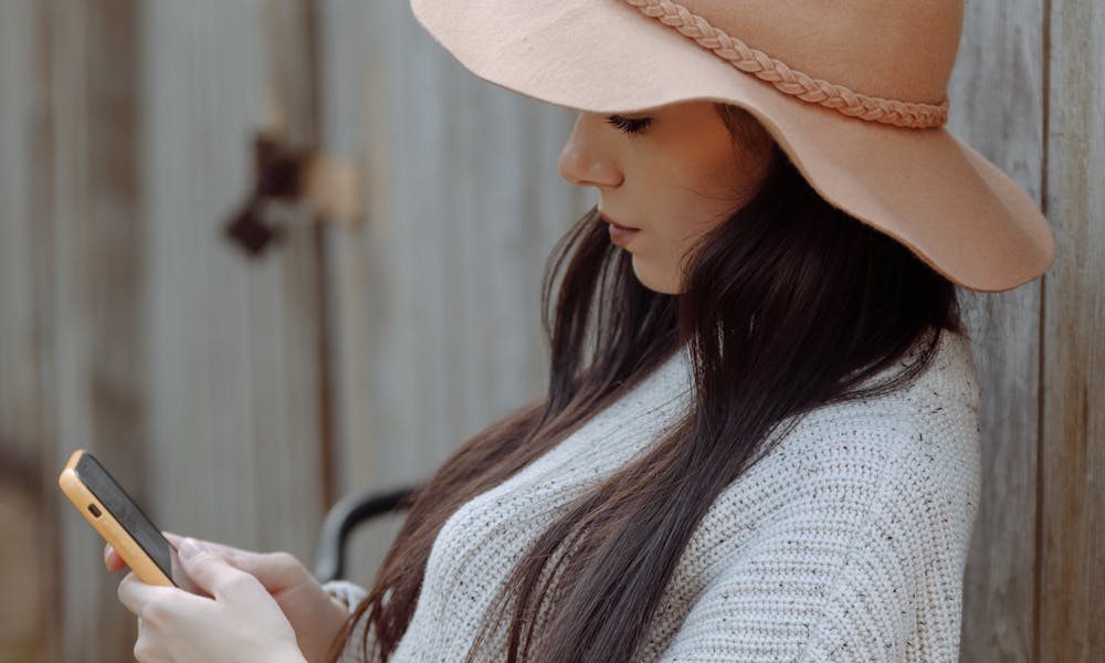 A Woman Wearing a Hat Using Her Smartphone .pexels