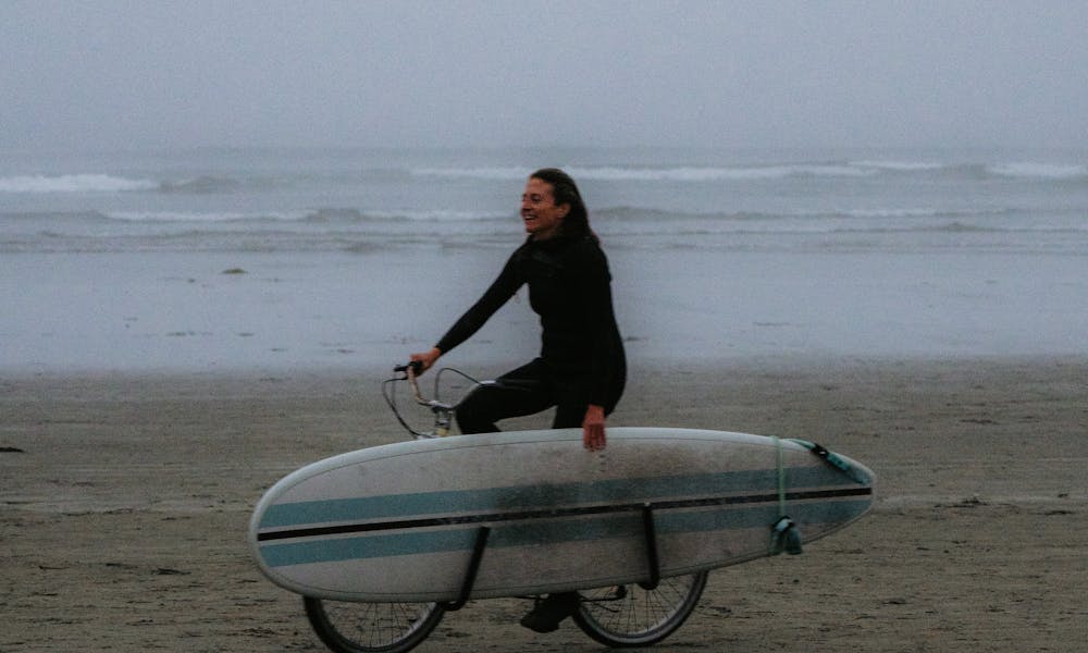Woman Riding Bike with Surfboard .pexels