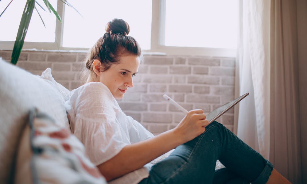 Woman Sitting on a Sofa and Using a Tablet  .pexels