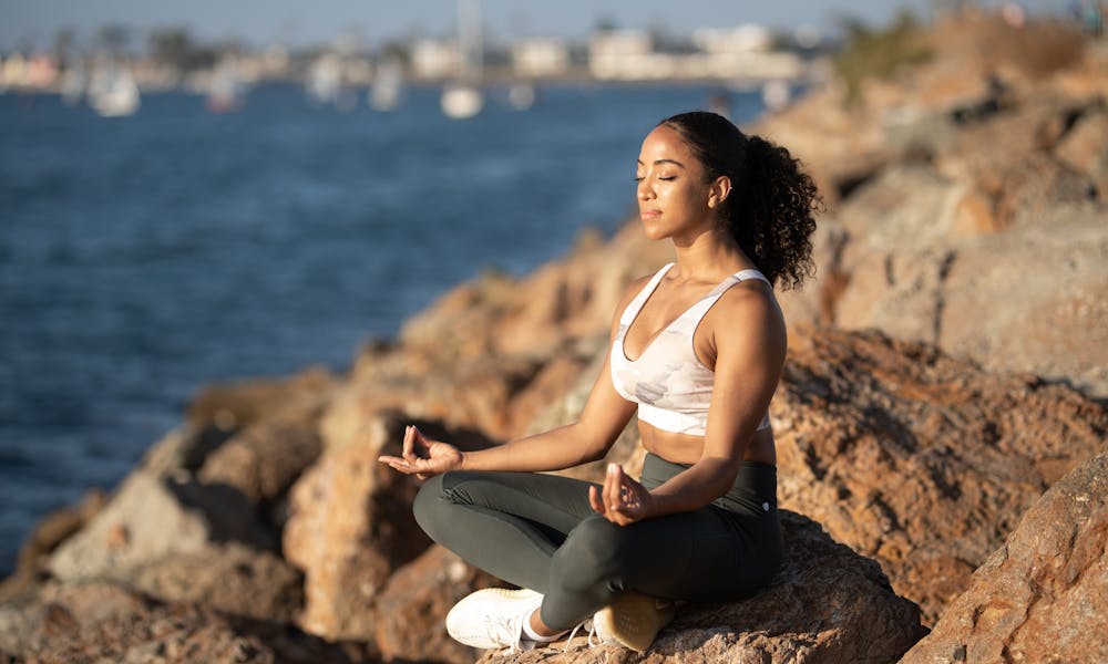 Woman Sitting on Rock While Doing Yoga .pexels