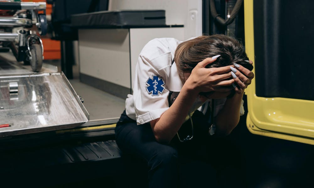 Distraught Paramedic Sitting with Her Head in Hands on the Bumper of an Ambulance .pexels
