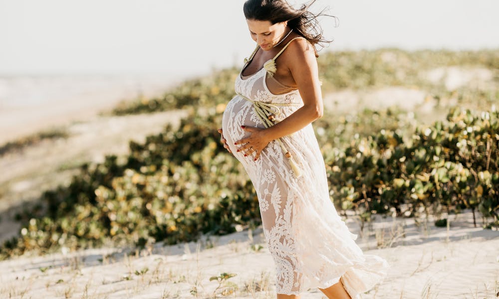 Pregnant Woman in White Dress Walking on Beach .pexels