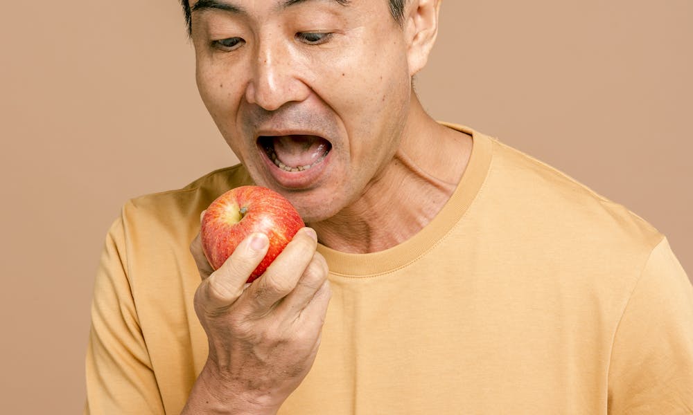 A Man in Yellow Crew Neck T-shirt Holding Red Apple Fruit .pexels