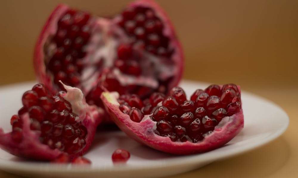 High-quality close-up of fresh pomegranate seeds on a white plate. .pexels