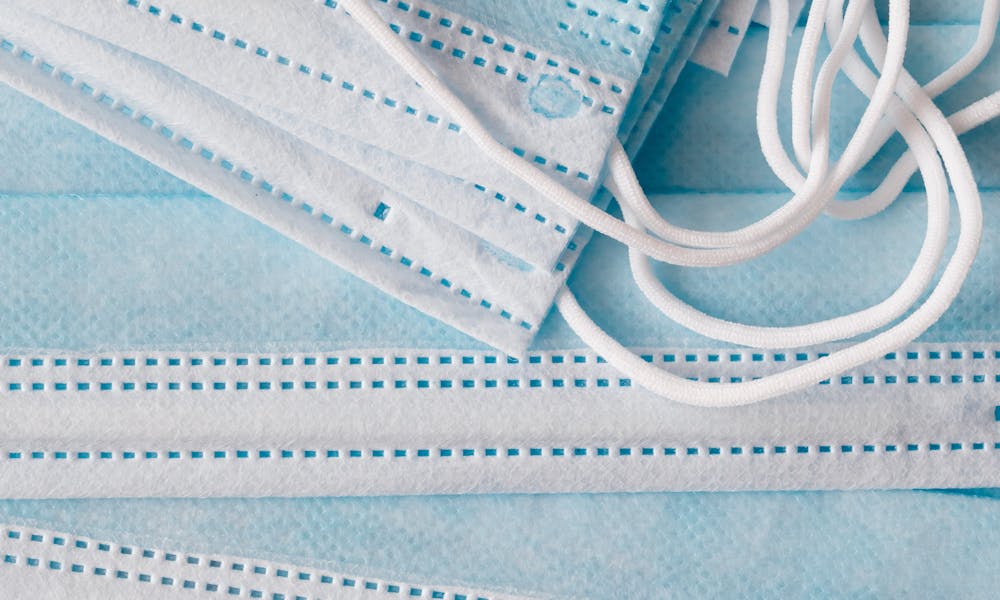 Top view of one use light blue medical respiratory protective face masks placed on top of each other in disorder .pexels