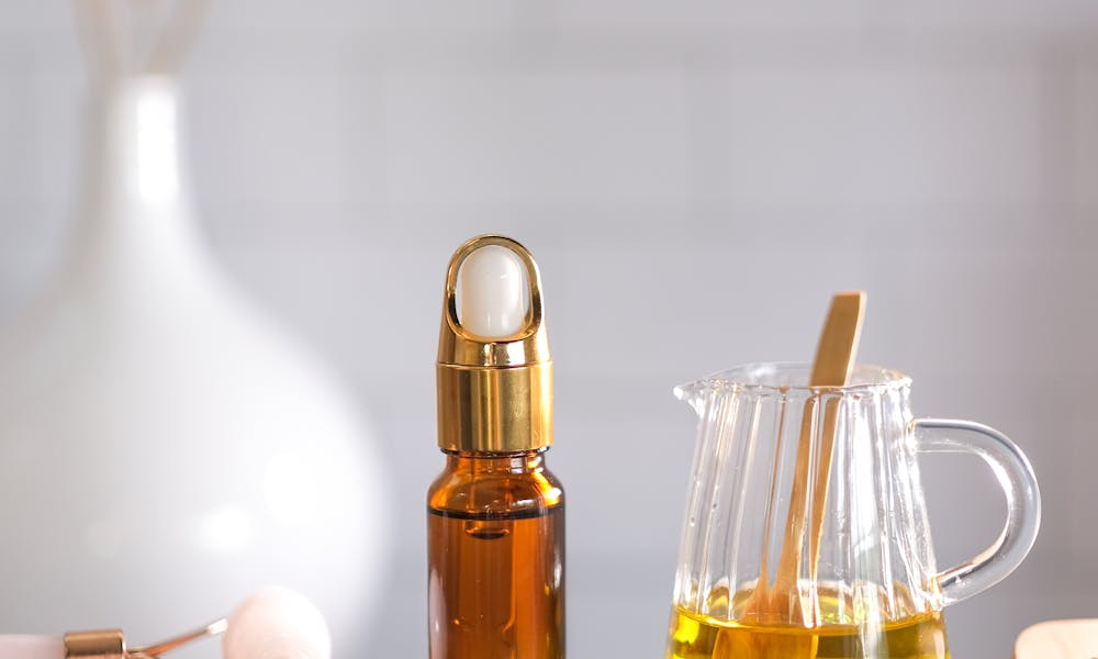 A serene spa setup featuring essential oils, a facial roller, and a soft towel for relaxation and wellness. .pexels