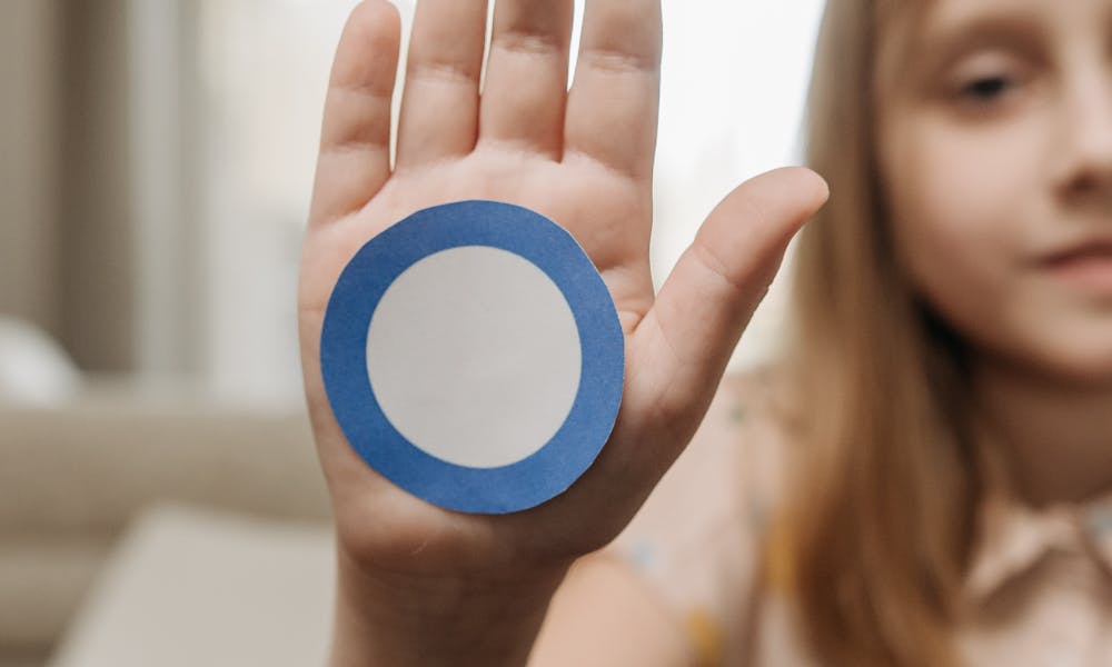 Close-up of a child showing a blue circle sticker for diabetes awareness. .pexels