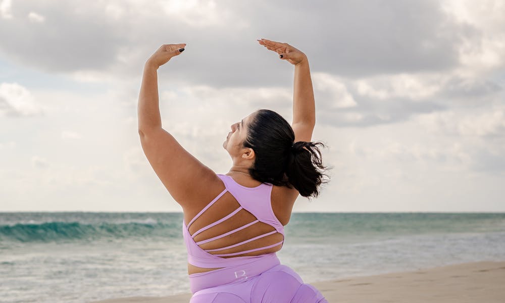 A woman performs yoga on a sandy beach, showcasing strength and flexibility in a serene coastal environment. .pexels