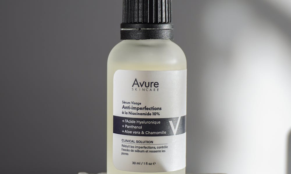 Minimalist photo of a skincare serum bottle on a textured surface. .pexels