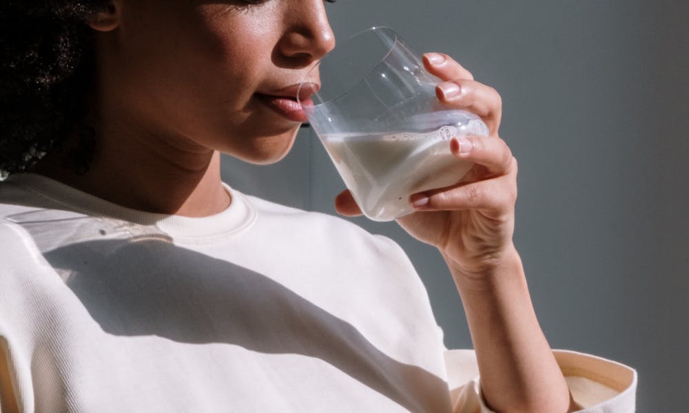 Pregnant African woman enjoying a glass of milk, symbolizing health and maternal care. .pexels