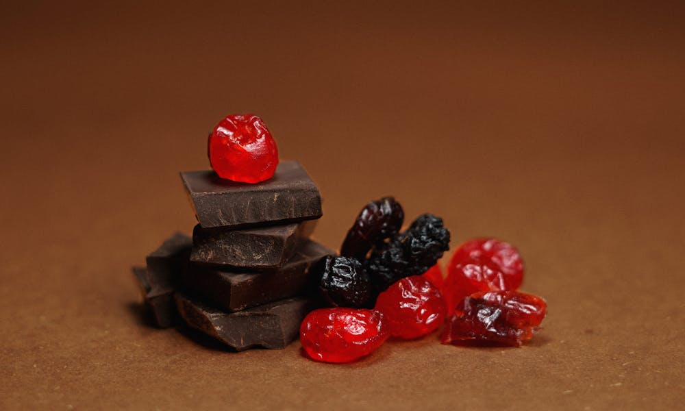 Indulgent dark chocolate pieces with vibrant berries against a rich brown backdrop, perfect for food lovers. .pexels
