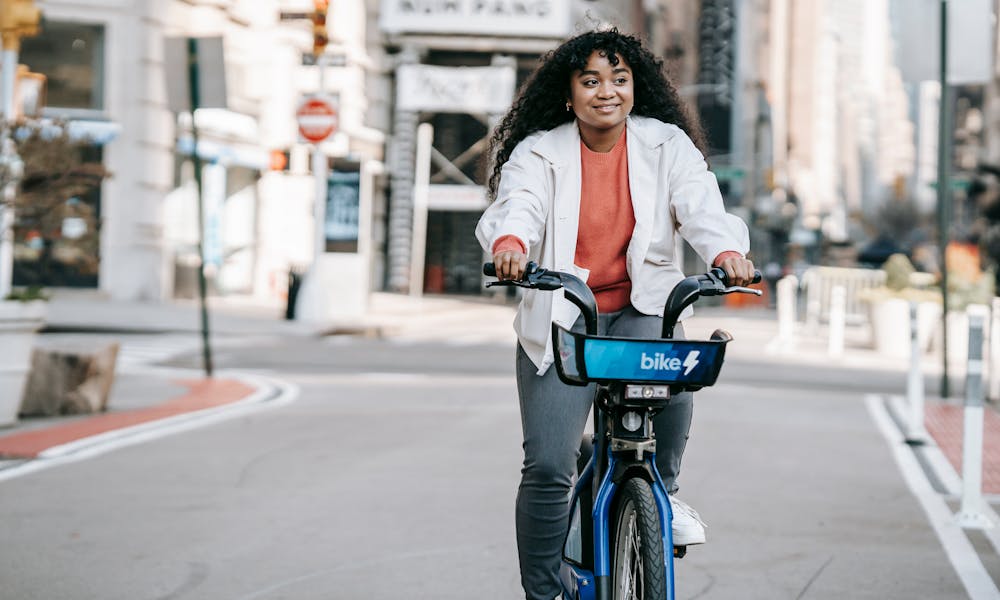 Content African American female in casual wear riding bicycle on modern city street in daylight .pexels