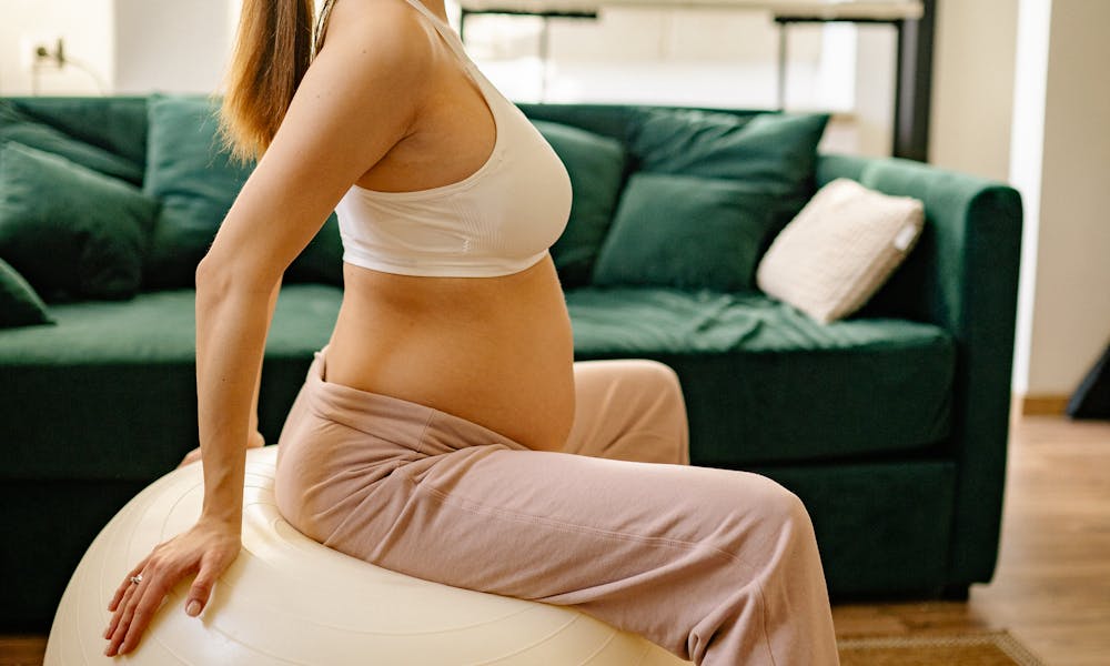 Expectant mother practicing prenatal exercise on a stability ball indoors. .pexels