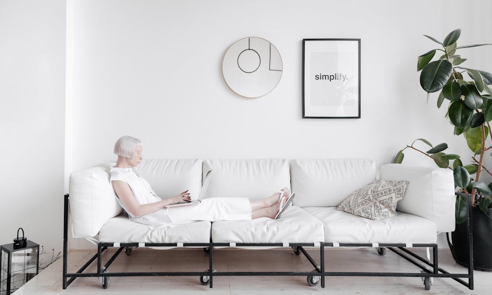 Elderly woman relaxing on a modern white sofa with a minimalist design theme. .pexels