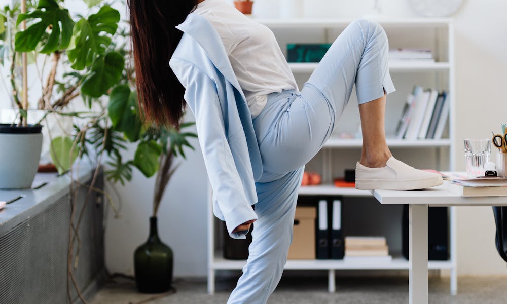 Business woman in blue suit stretching in bright office space, promoting workplace wellness. .pexels