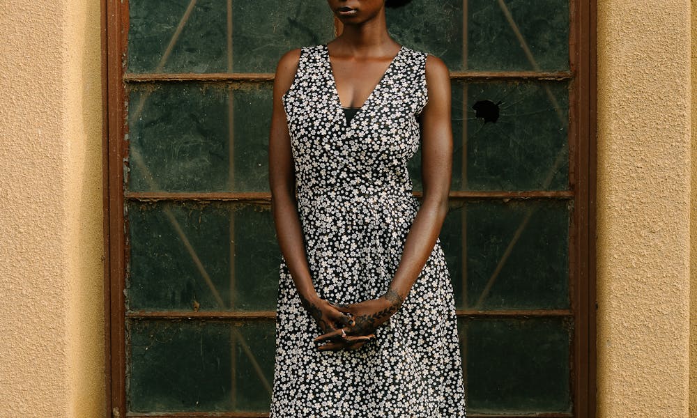 Stylish woman in a floral patterned dress and headscarf standing outdoors by a vintage door. .pexels