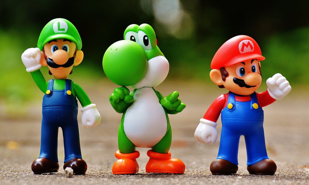Vibrant Super Mario, Luigi, and Yoshi figures arranged outdoors on a sunny day. .pexels