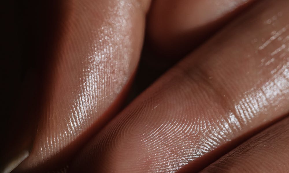 Close-up shot of fingers with smooth skin, showing delicate texture and light reflection. .pexels