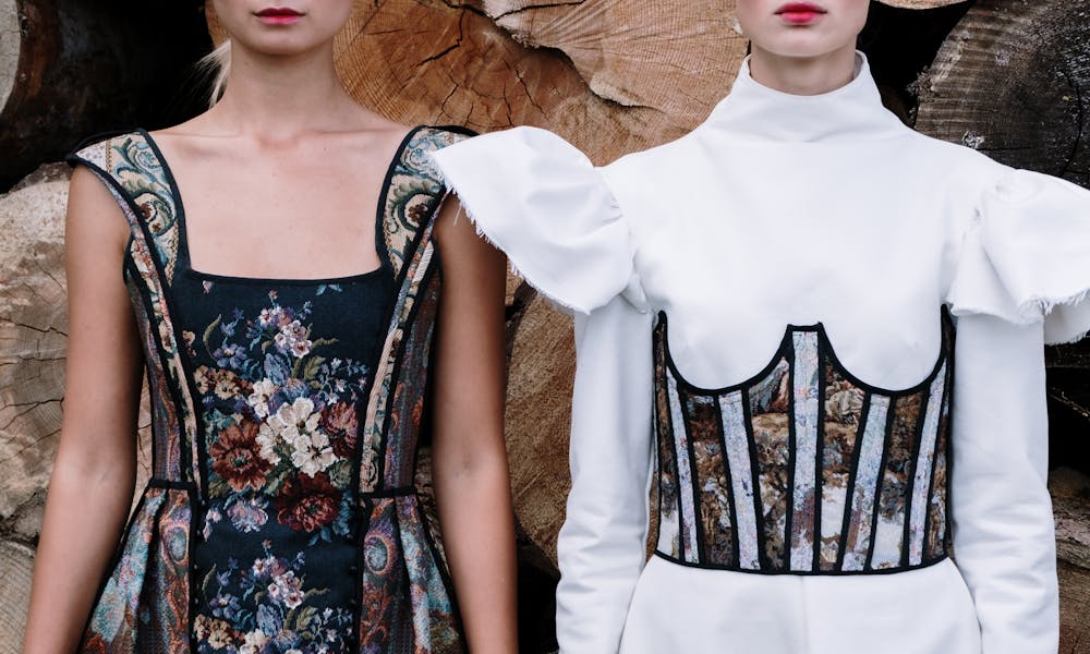 Two models showcase stylish and elegant fashion designs with floral patterns and dramatic textures. .pexels
