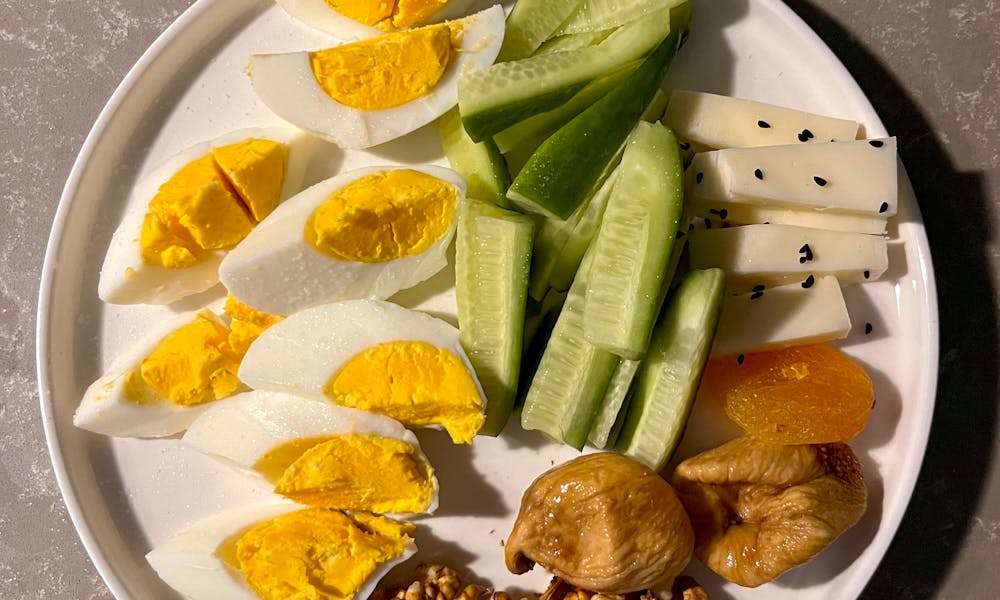 Colorful platter with boiled eggs, cucumbers, cheese, nuts, and dried fruits. .pexels