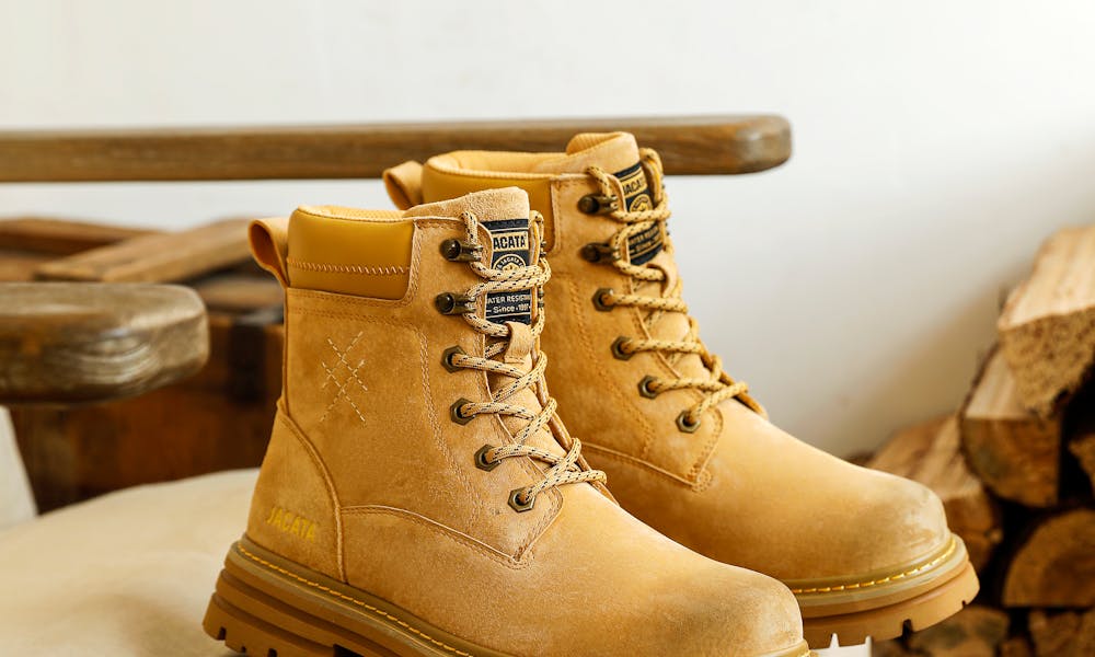 Tan leather boots on a wooden chair with firewood, showcasing rustic style. .pexels