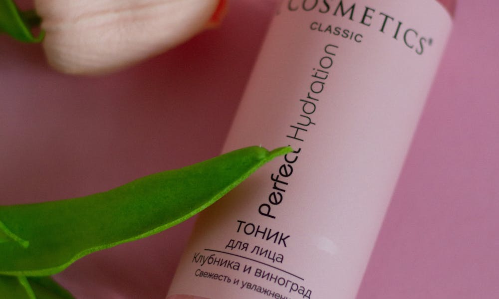 Perfume bottle arranged with tulips on a soft pink surface, embodying beauty and elegance. .pexels