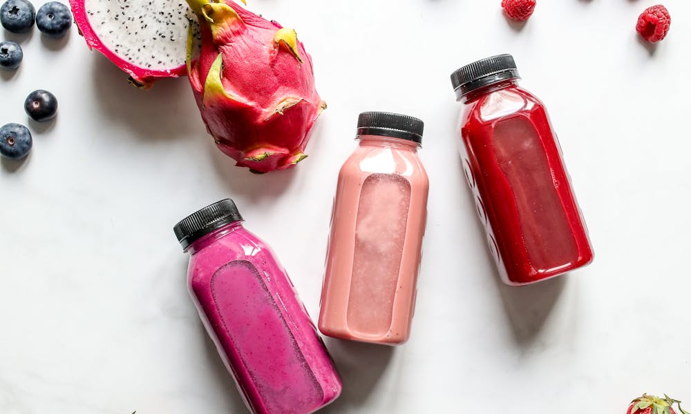 Colorful fruit smoothies with dragon fruit, berries, and more on a white background. .pexels